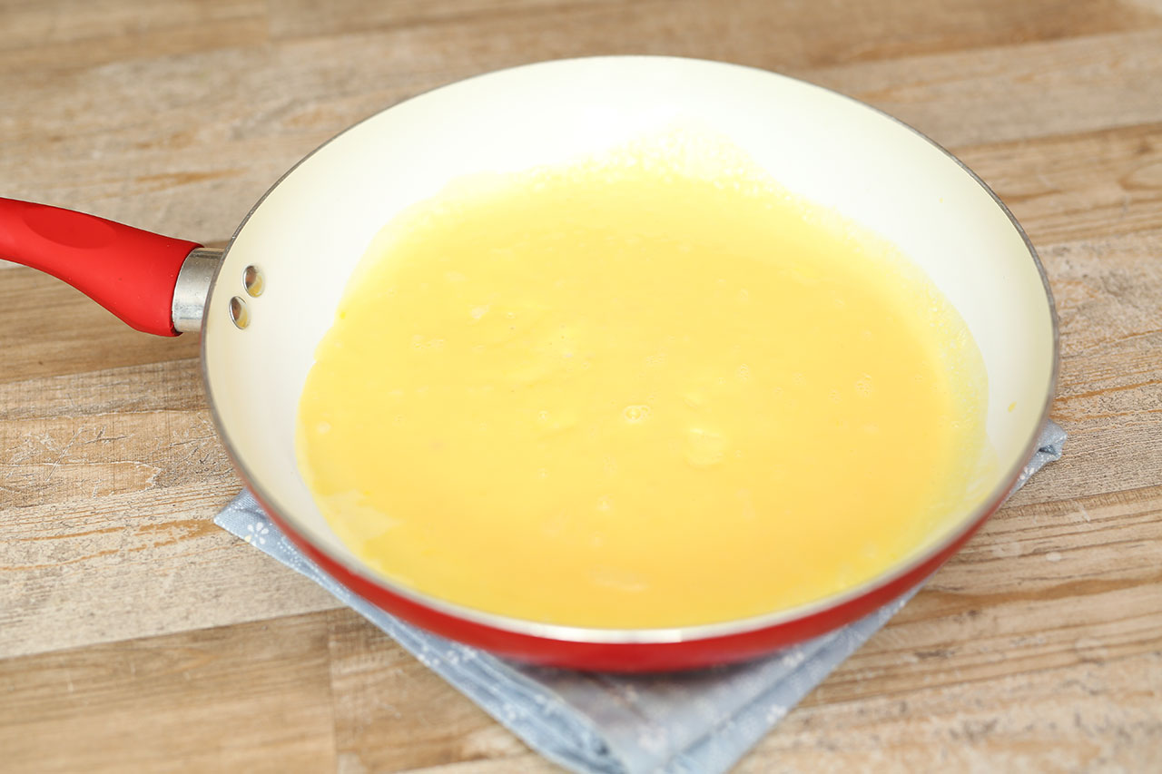 Gebe etwas Rapsöl in eine beschichte Pfanne und erhitze sie. Füge dann den Ei-Milch-Mix in die beschichtete Pfanne. Lass die Eimasse stocken. Die Unterseite sollte leicht braun sein und die Oberseite cremig.
Dann nimmst du vorsichtig das Omelette aus der